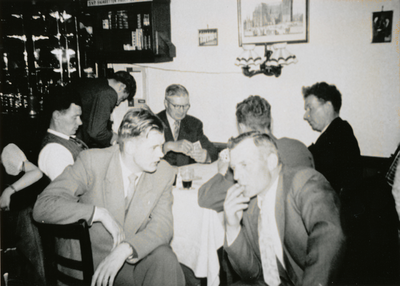 875947 Groepsportret van kaartende en toekijkende bezoekers in café Van Rijnsoever (St. Jacobsstraat 7) in Wijk C te ...